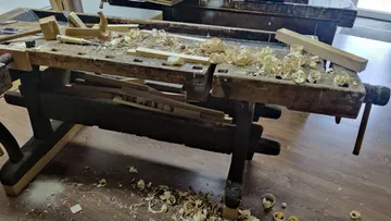 Woodworking bench with shavings in workshop.