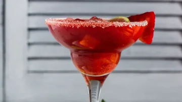 Ein Cocktailglas mit rotem Getränk und Zuckerrand.