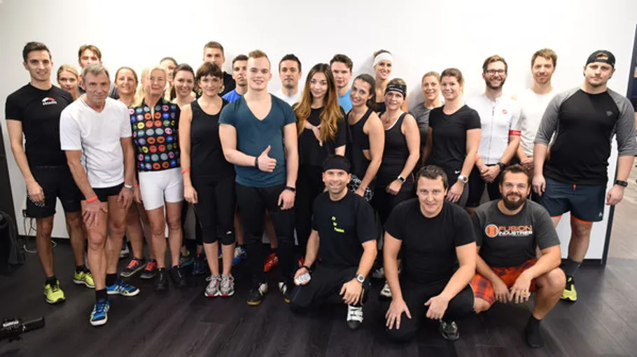 Gruppe von Sportlern posiert fröhlich vor einer Wand.