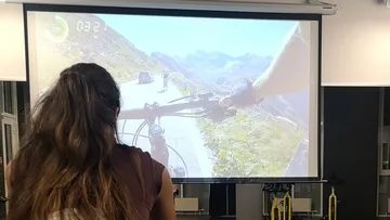 Person rides a bike, looks at virtual landscape on canvas.