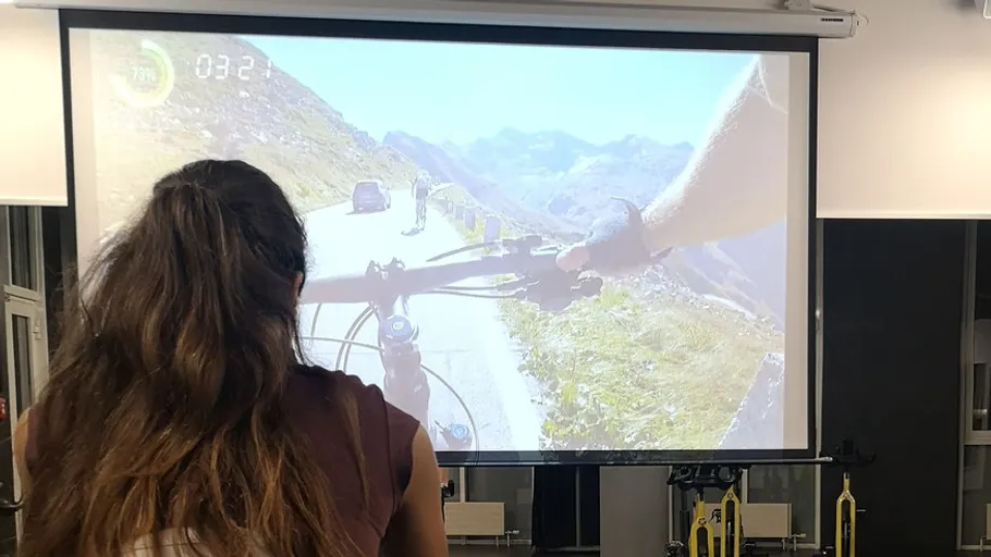 Person fährt Rad, betrachtet virtuelle Landschaft auf Leinwand.