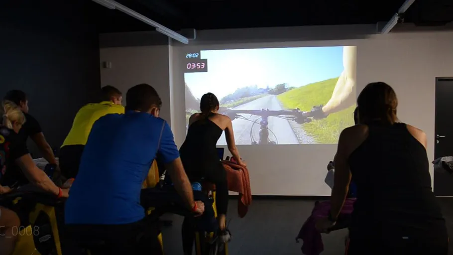 Group of people on bikes, in front of a projection screen.