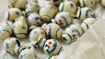 Ceramic jugs are scattered on paper, some with writing.