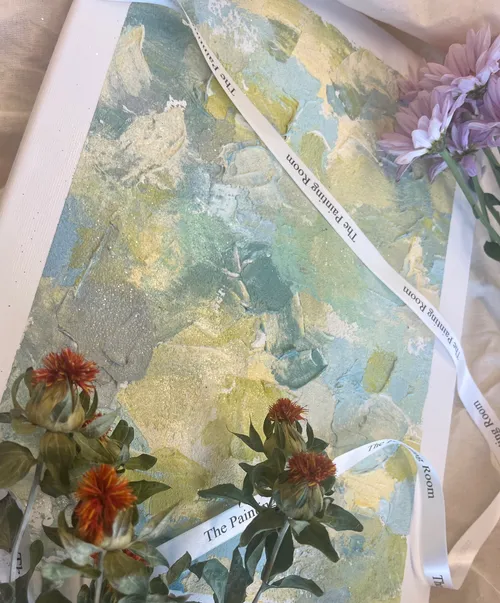 Pastel-colored painting surrounded by flowers and ribbons.