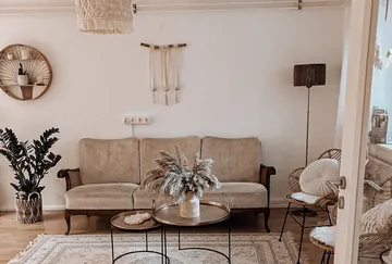 Gemütliches Wohnzimmer mit beigem Sofa, Zierpflanzen.