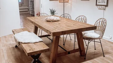 Holztisch mit Stühlen und Bank im Zimmer.