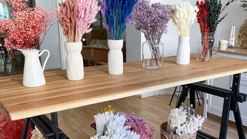 Bunte Trockenblumen in Vasen auf Holztisch.