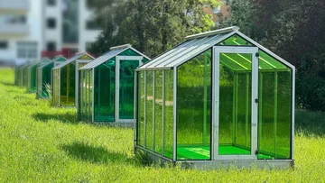 There are several greenhouses in a green meadow.