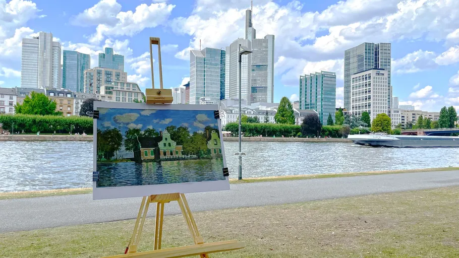 Painting on easel observed from modern high-rise buildings on the river.