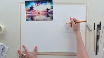 Eine Hand zeichnet einen Heißluftballon auf Papier.