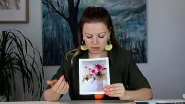 Frau hält ein Foto mit Blumen in einem Raum.