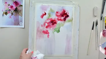 Wasserfarbe malt Blumen, Künstlerhand hält Tuch, kreative Umgebung.