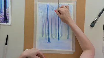 A unique hand paints trees on transparent watercolor surface.