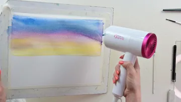 Fön hält ein Gemälde trocken in einem kreativen Raum.