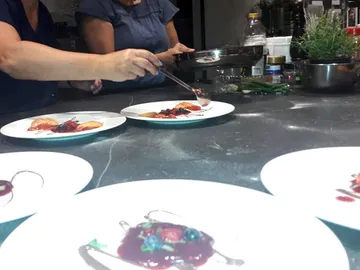 Zwei Frauen richten kunstvolles Essen auf Tellern an.