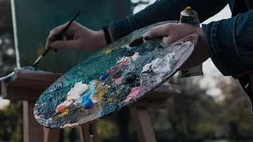 Palette with paints, hand painting on outdoor canvas.