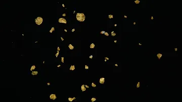 Goldene Partikel schweben im Dunkeln.