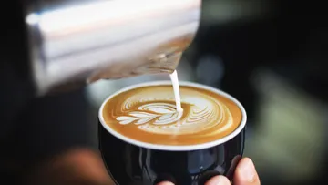 Kaffeetasse wird mit aufgeschäumter Milch dekoriert.