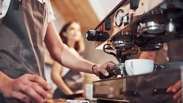 Barista serves coffee maker in a café.