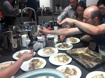 Gemeinsames Essen, Menschen servieren Fischgerichte auf Tellern.