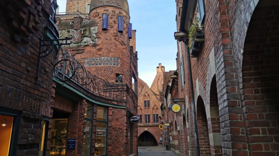 Enger, gepflasterter Weg zwischen historischen Backsteingebäuden.