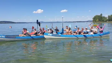 Zwei Kajaks mit Menschen fahren auf einem ruhigen See.