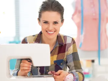 Woman sewing on a sewing machine in a bright room.