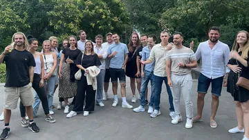 Gruppe von Menschen posiert, lächelt in einem Park.