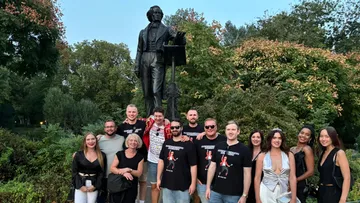 Gruppe von Personen posiert vor einer Statue im Park.
