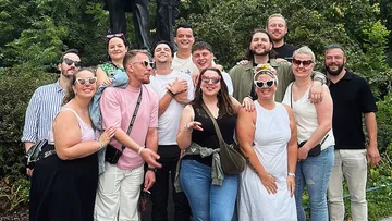 Group photo of twelve people wearing sunglasses outdoors.