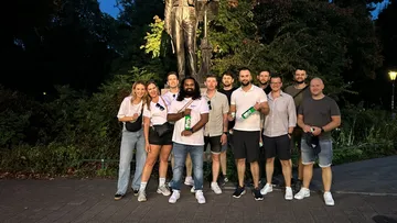 Group of people pose in front of a statue in the park.