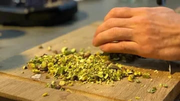 Hand cut pistachios on a wooden board in the kitchen.