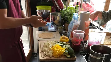 Cooking person cuts vegetables in a bright kitchen.
