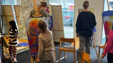 Künstler malen auf Staffeleien in einem kreativen Raum.