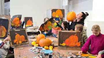 Children draw pumpkins in a creative class.