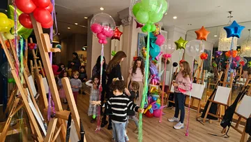 Children play and party with balloons in a room.