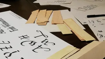 Papers and pieces of wood are lying on a table.