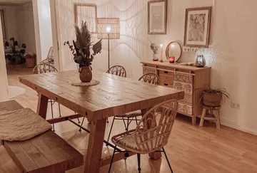 Wooden dining table with wicker chairs, warm decor.