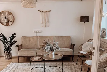 Gemütliches Wohnzimmer mit beigem Sofa, Dekor, Pflanzen.