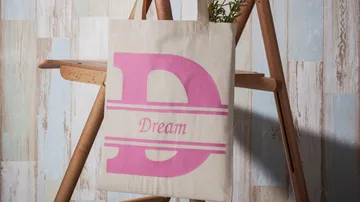A cloth bag hangs on a stand with the inscription “Dream.”