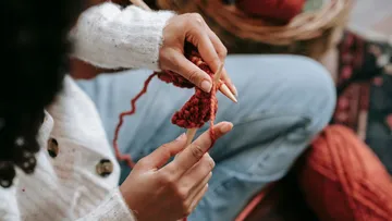 Knit hands with wool in a cozy room.