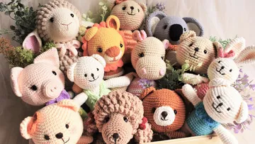 Crocheted animals sit together surrounded by plants and flowers.