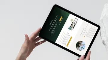 Tablet is held, shows a website with information.