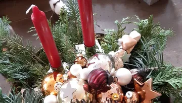 Red candles stand in a shiny, festive wreath.