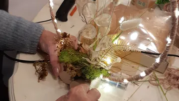 Hands create a decorative flower arrangement with lights.