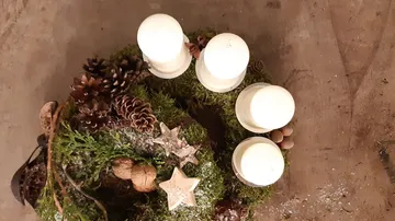 An advent wreath with candles, pine cones and moss.