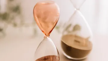 Two hourglasses are on a table; one is running.