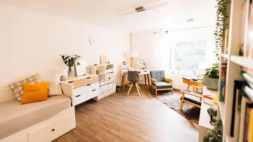 Helles Zimmer mit Möbeln, Pflanzen und gemütlicher Atmosphäre.