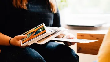 Eine Person hält mehrere Zeitschriften und betrachtet sie.