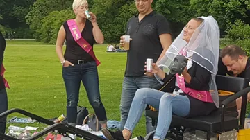 Young woman wearing a veil drinks and sits on a wagon.